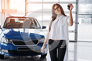 Young happy woman near the car with keys in hand