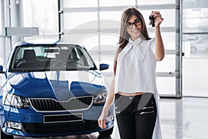 Young happy woman near the car with keys in hand