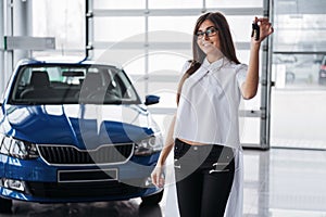 Young happy woman near the car with keys in hand