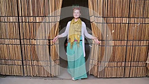 Young happy woman opening curtain made of palm