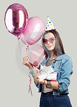 Young happy woman with pink gift box and balloons