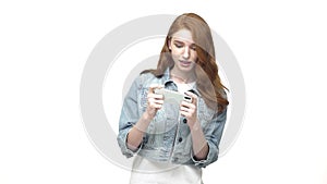 Young, happy woman playing game on smartphone on white studio, super slow motion