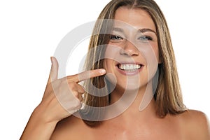 Young happy woman pointing on her beautiful and white teeth