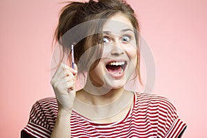 Young happy woman with positive result result of a one-time pregnancy test, excited future mother, family planning, motherhood