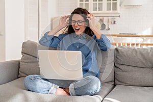 Young happy woman with raised hands looking on laptop screen with lottery victory or job offer email