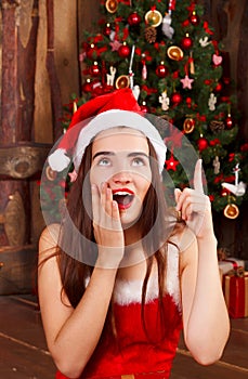 Young happy woman in red santa hat and red dress sitting near ne