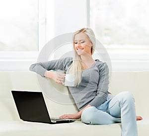 Young and happy woman resting on sofa at home and drinking coffee