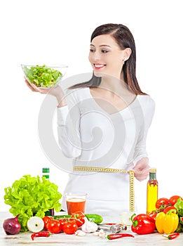 Young happy woman with salad measuring her waistline.