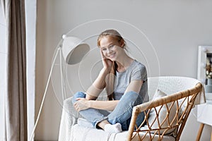 Young happy woman sitting on modern chair enjoying morning at home