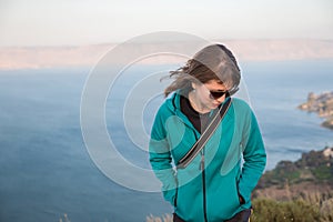 Young happy woman standing above lake, sea.