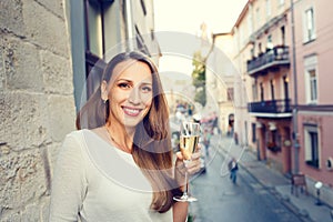 Young happy woman standing with glass of champagne