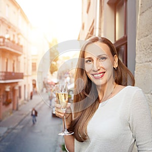 Young happy woman standing with glass of champagne