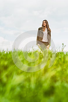 Young happy woman standing outside in green field