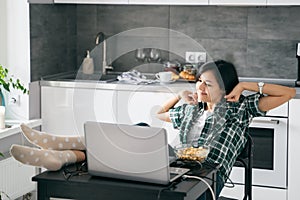 Mladý šťastný žena strečing relaxačné zatiaľ čo pracovné na prenosný počítač v kuchyňa na. vzdialenosť alebo pripojený do internetovej siete vzdelanie 