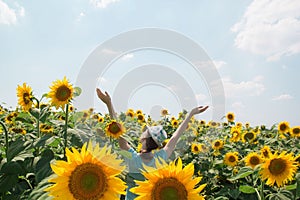 Young happy woman in sunflower field enjoying summer