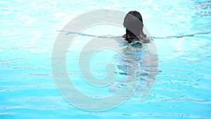 Young happy woman swimming in a swimming pool