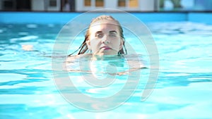 Young happy woman swimming in a swimming pool