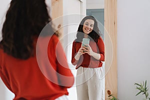 Young happy woman taking a selfie in front of the mirror