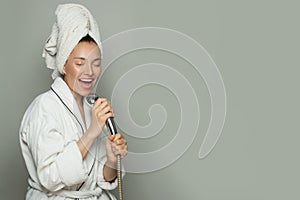 Young happy woman taking a shower and singing