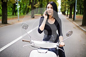 Young happy woman talking mobile phone on scooter