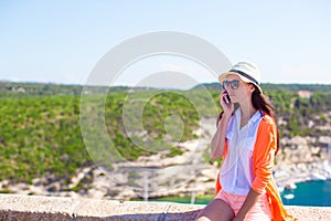 Young happy woman talking by phone outdoors with