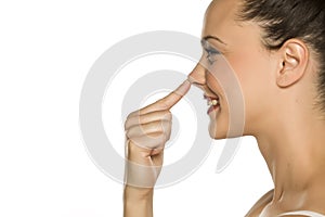 Young happy woman touches her nose with her finger