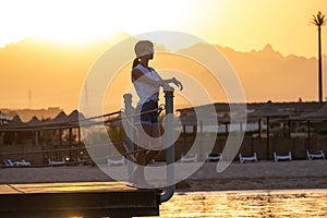 Young happy woman tourist relaxing outdoors on warm sunny evening on sea shore. Summer vacations and travelling concept