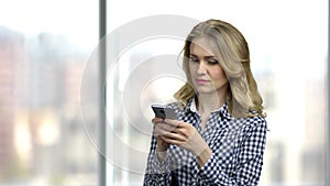 Young happy woman typing text message on phone.