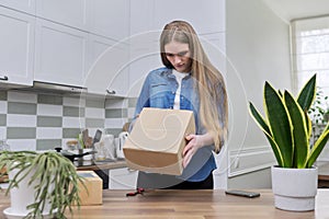 Young happy woman unpacking cardboard boxes, unboxing expected postal parcel