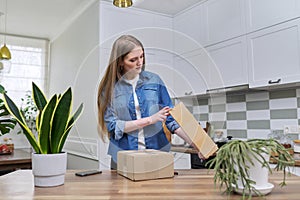 Young happy woman unpacking cardboard boxes, unboxing expected postal parcel