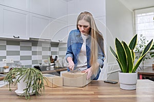 Young happy woman unpacking cardboard boxes, unboxing expected postal parcel