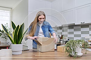 Young happy woman unpacking cardboard boxes, unboxing expected postal parcel