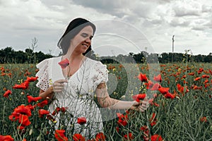 Young happy woman walking in a blooming poppy field