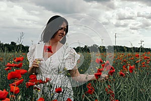 Young happy woman walking in a blooming poppy field