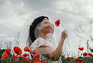 Young happy woman walking in a blooming poppy field