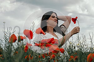 Young happy woman walking in a blooming poppy field