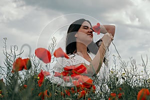 Young happy woman walking in a blooming poppy field