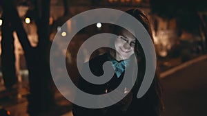 Young happy woman walking in park near the Colosseum in Rome, Italy and using the smartphone in the evening.