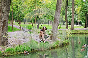 Young happy woman walking in the rain in green park with umbrella, smiling, fun. person sitting on the bench. Cold weather