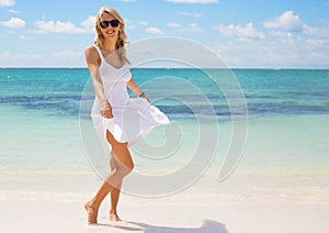 Young happy woman in white dress on the beach