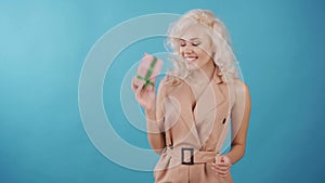 Young happy woman win a gift. Studio video on the smooth blue background.