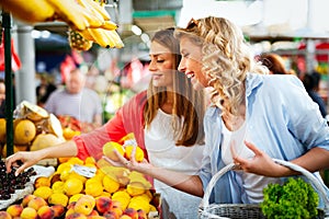 Young happy women shopping vegetables and fruits on the market