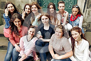 Young happy women sitting on stairs posing on background of old european city street, stylish hipster girls, moments of happiness