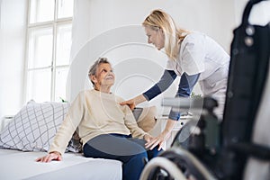 A health visitor talking to a senior woman sitting on bed at home. photo