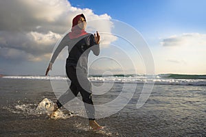 Young healthy and active runner Muslim woman in Islam hijab head scarf running and jogging on the beach wearing traditional arab