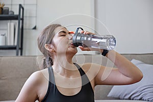 Young healthy Asian woman holds a water bottle for practicing yoga online or exercising at home.