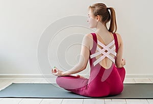 Young healthy beautiful woman practicing yoga at home sitting in lotus pose on yoga mat meditating relaxed. Indoor and