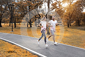 Young and healthy couple people are in love jogging in the park during autumn season healthy or valentine concept