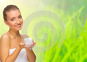 Young healthy girl with body cream jar on spring background