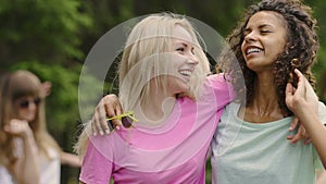 Young healthy girls hugging, smiling at camera, dancing with friends outdoors